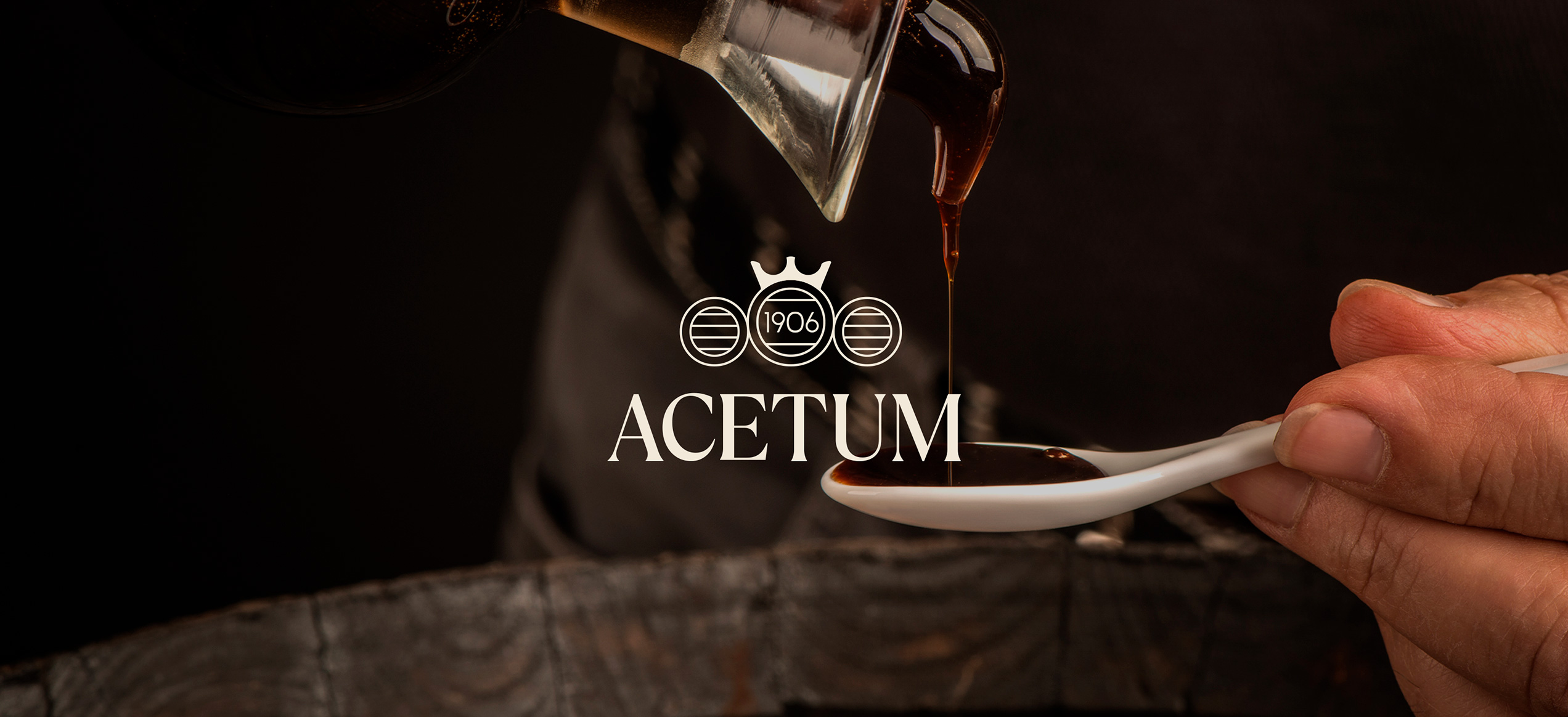 Dettaglio di aceto balsamico versato su un cucchiaio, con logo Acetum in sovrimpressione