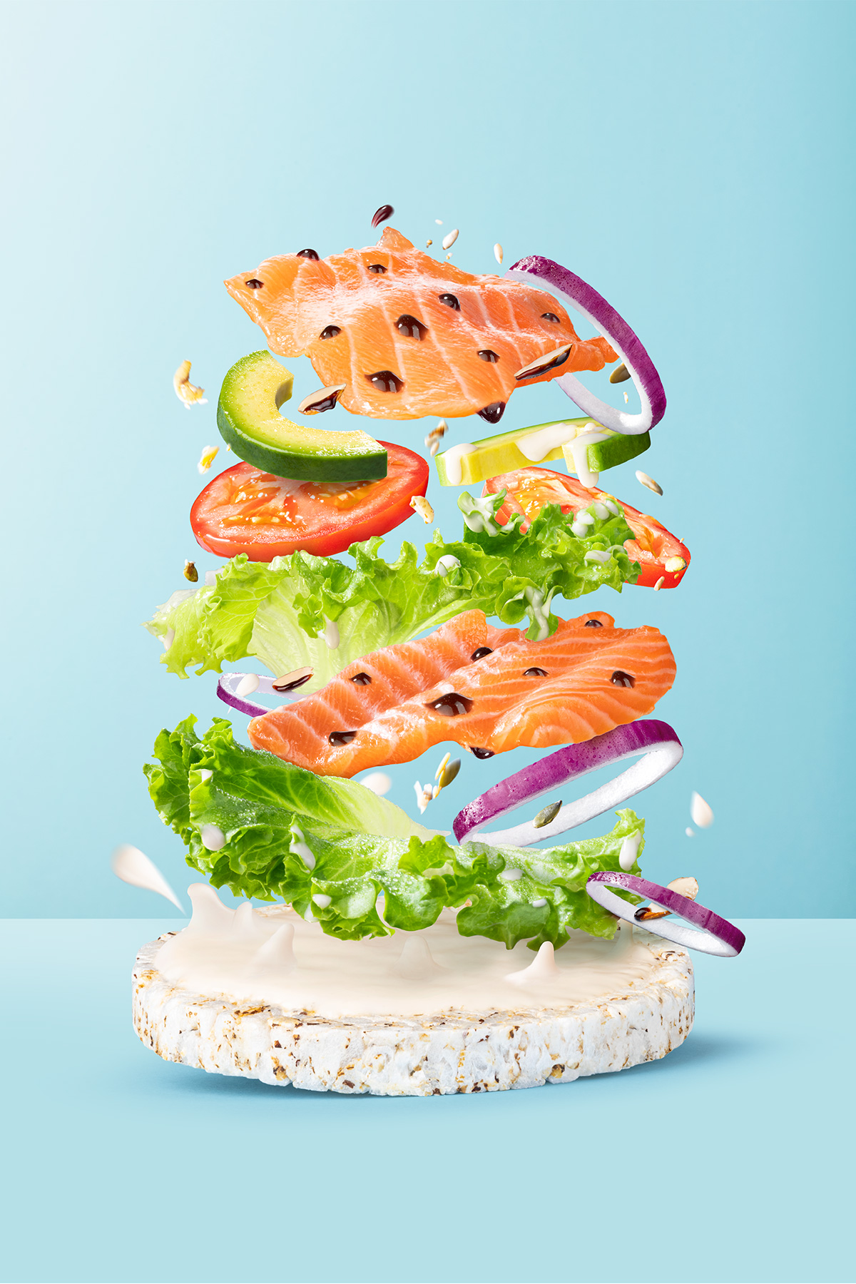 Composizione creativa con salmone, verdure e salsa su galletta Che Bon come base, su sfondo azzurro