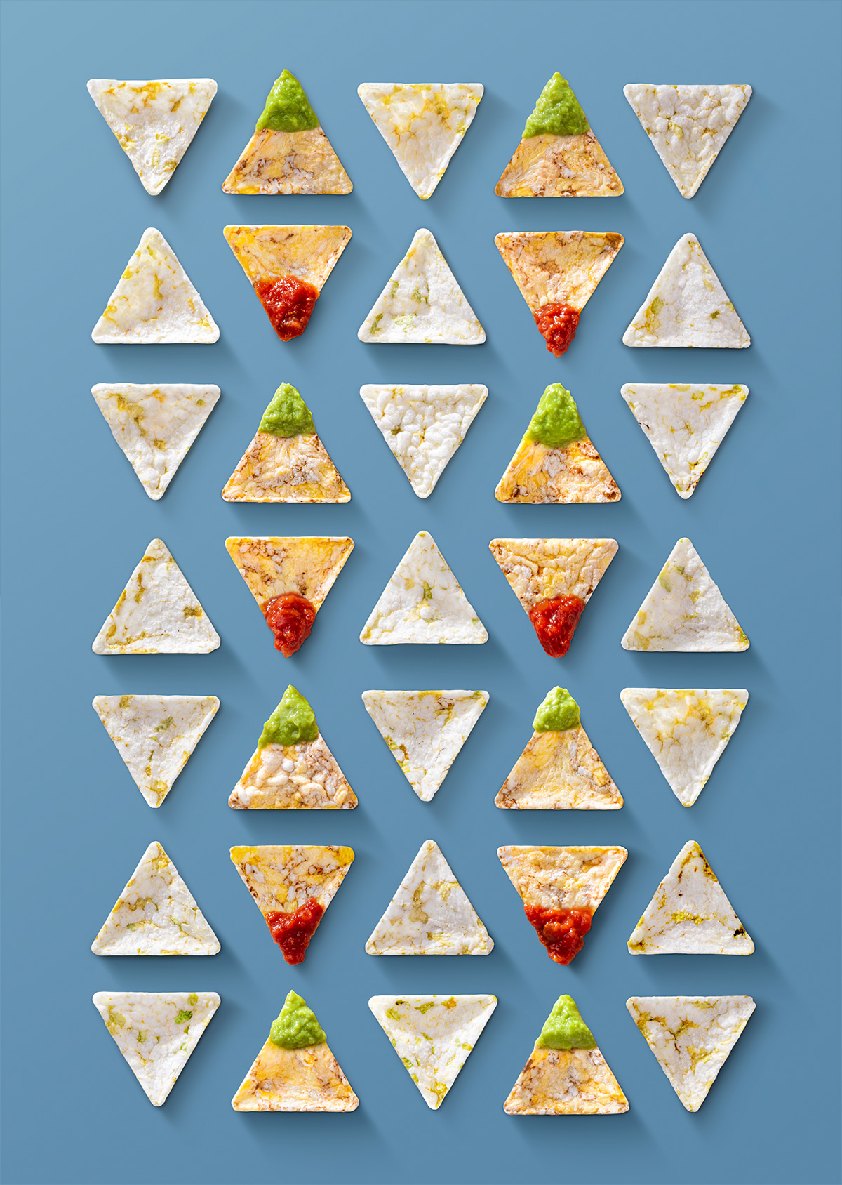 Griglia di snack triangolari Che Bon con topping di guacamole e salsa rossa, su sfondo azzurro