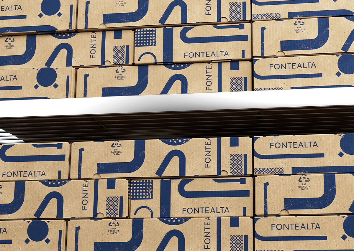 Muro composto da scatole di cartone sovrapposte con stampa blu del pattern grafico Fontealta, che richiama forme e linee dell’universo idraulico