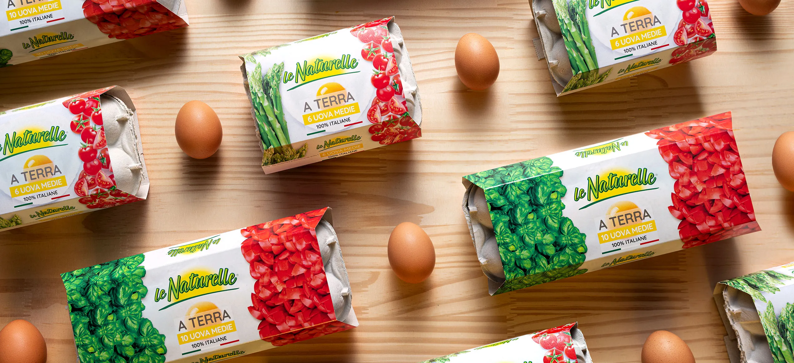 Packaging uova Le Naturelle Tricolore con grafiche verdi, rosse e ingredienti naturali, su fondo di legno chiaro