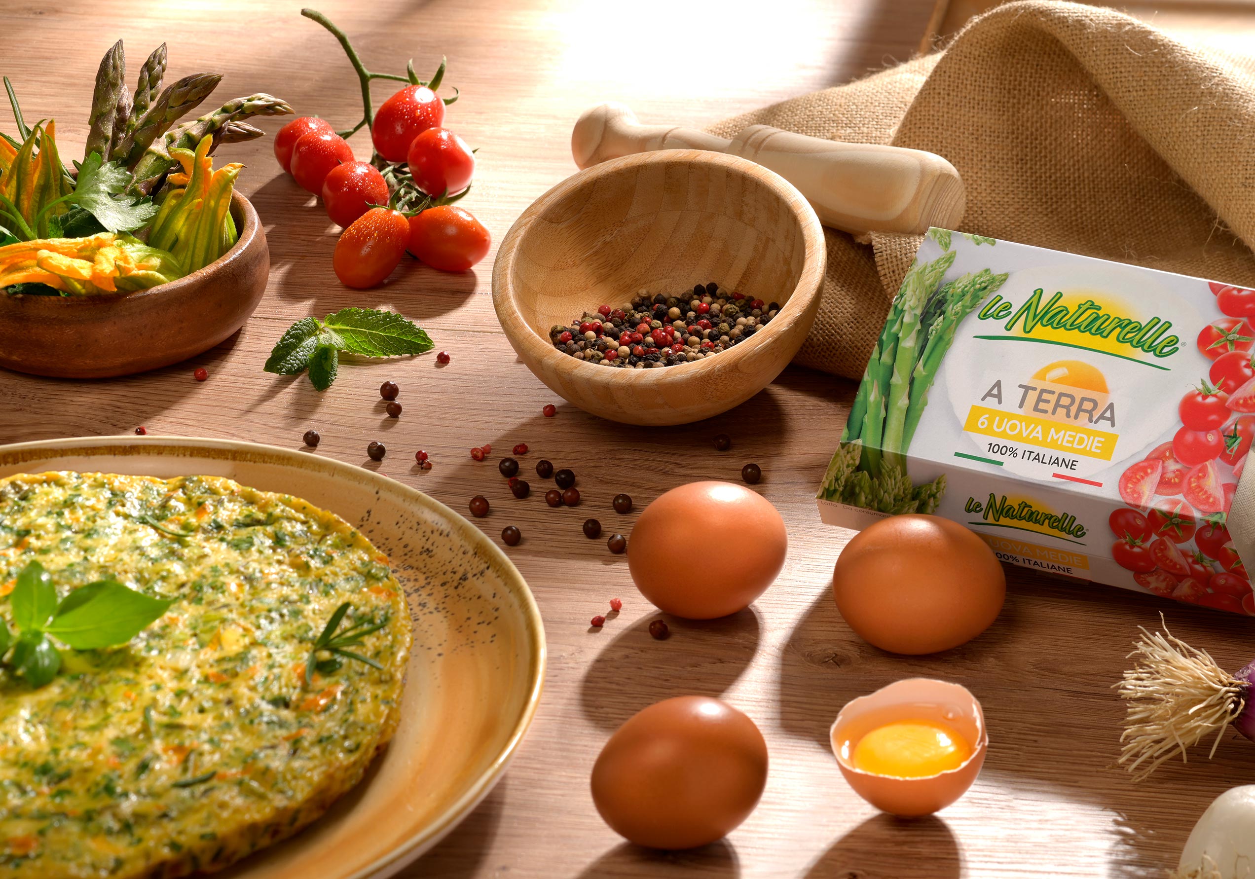 Tortino alle verdure con uova Le Naturelle, ortaggi freschi e spezie su tavolo rustico in legno