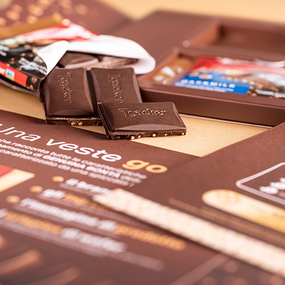 Quadretti di cioccolato fondente Loacker con interno croccante, disposti su pieghevole del kit Choco-Crisp