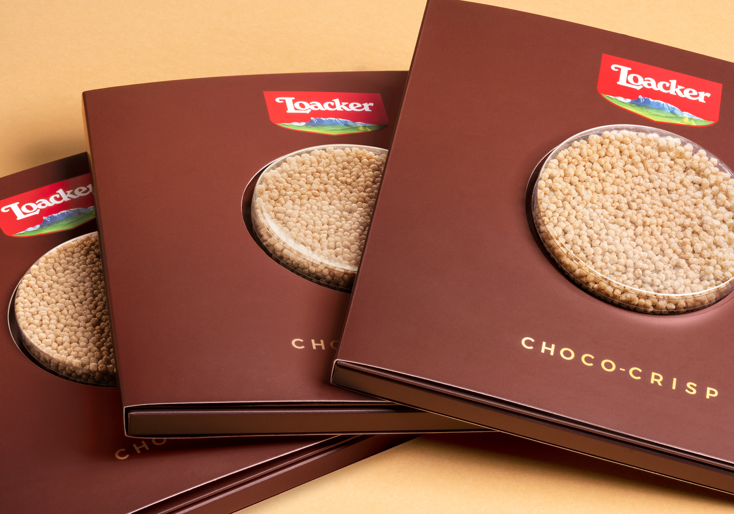 Tre confezioni Loacker Choco-Crisp impilate in diagonale, con finestra trasparente centrale e logo ben visibile