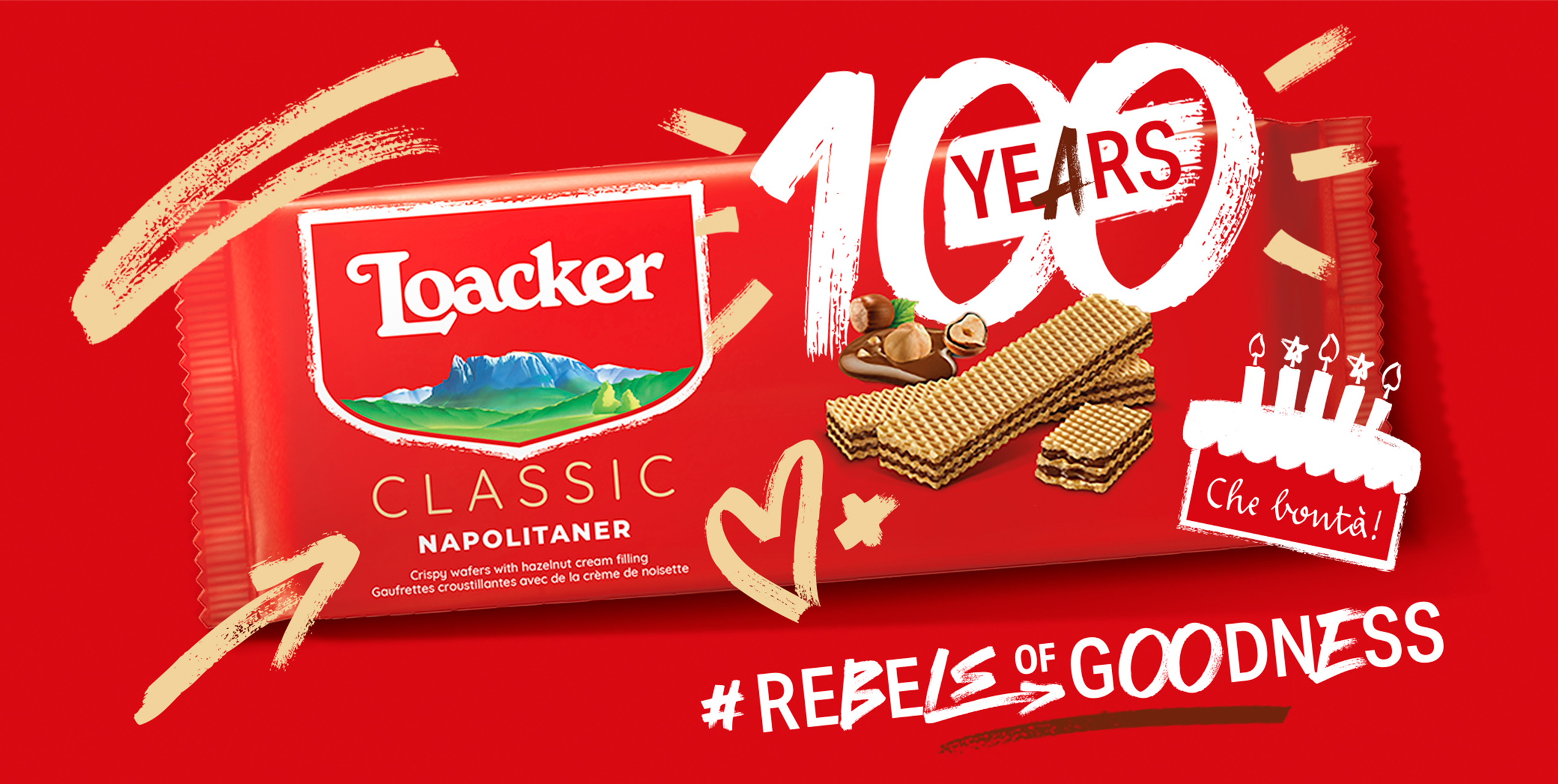 Confezione Loacker Classic Napolitaner con scritta “100 Years”, torta celebrativa, nocciole e hashtag #RebelsOfGoodness