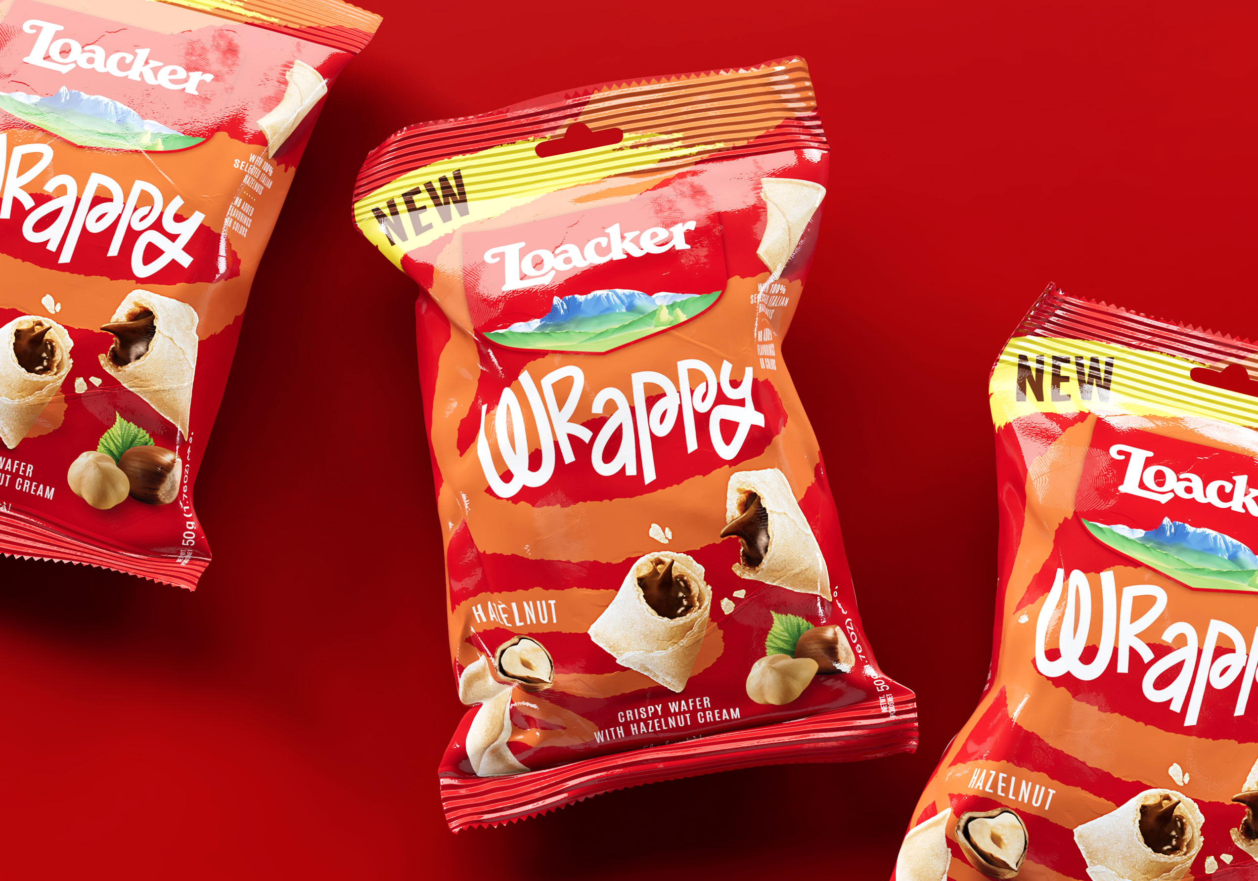 Tre confezioni Loacker Wrappy hazelnut su fondo rosso brillante, in evidenza il design del pack